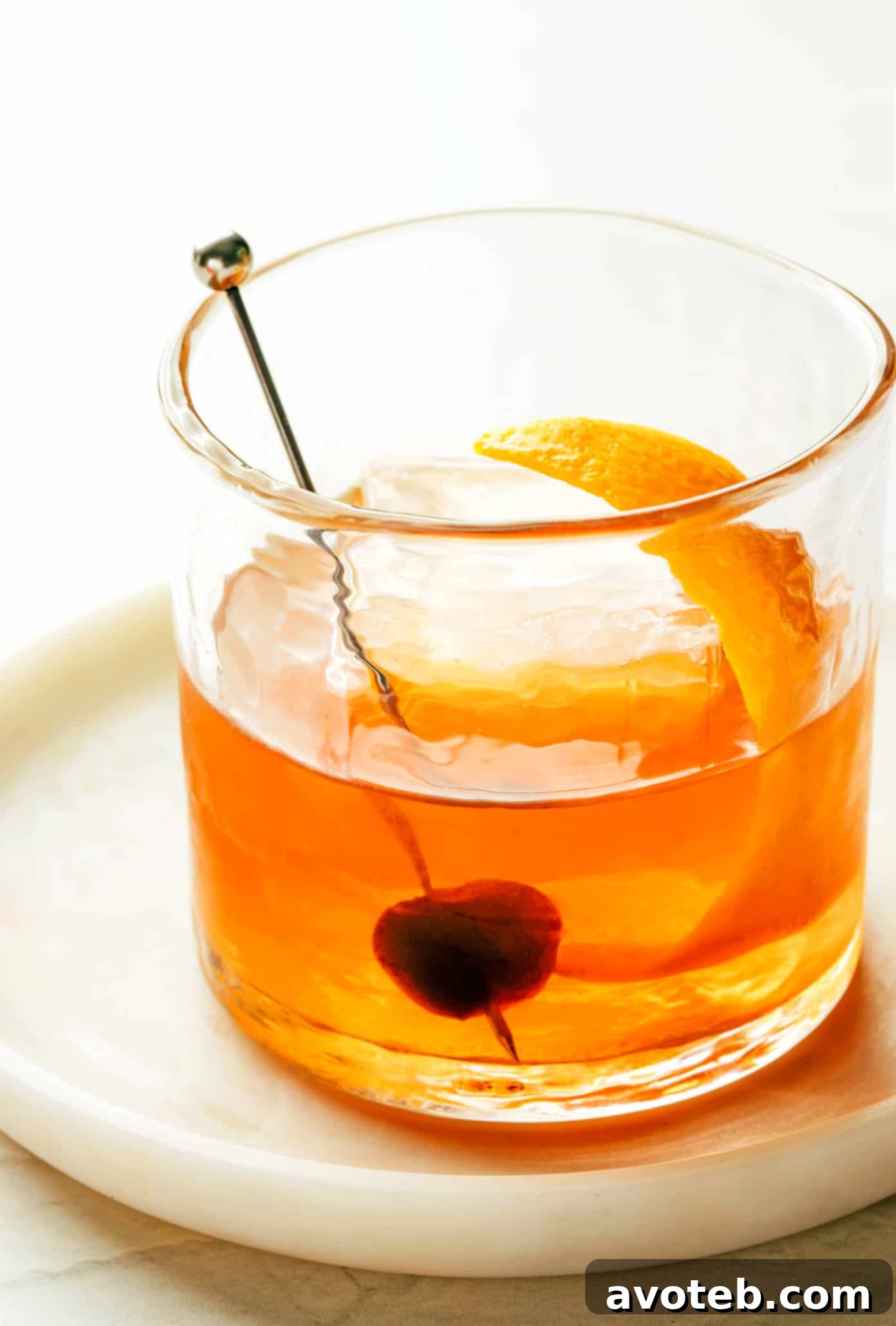 The classic Old Fashioned cocktail, a timeless icon of mixology. A refreshing Old Fashioned cocktail served in a classic lowball glass with a large ice cube.