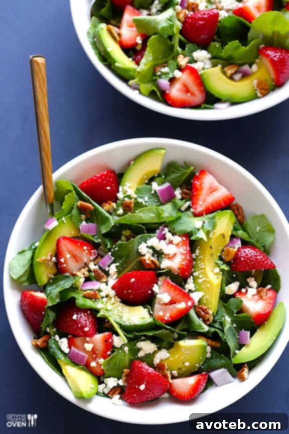 Healthy Strawberry Kale Salad Recipe Overhead view of a prepared Strawberry Kale Salad, featuring thinly sliced red onion, goat cheese, and toasted pecans.