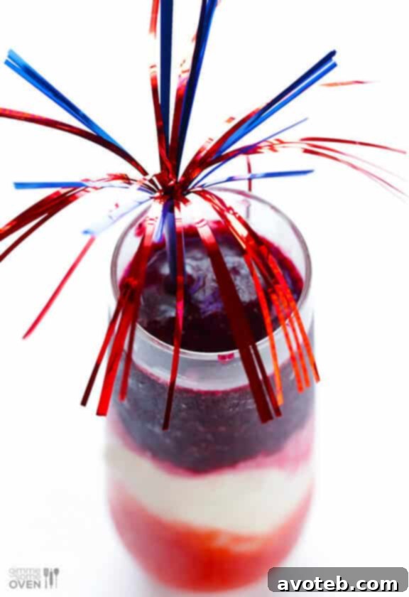 A beautifully layered Red, White & Blue(berry) Margarita, garnished with a lime wedge and a small firecracker pick, ready for a patriotic celebration. #4thofjulycocktail #memorialdaydrink
