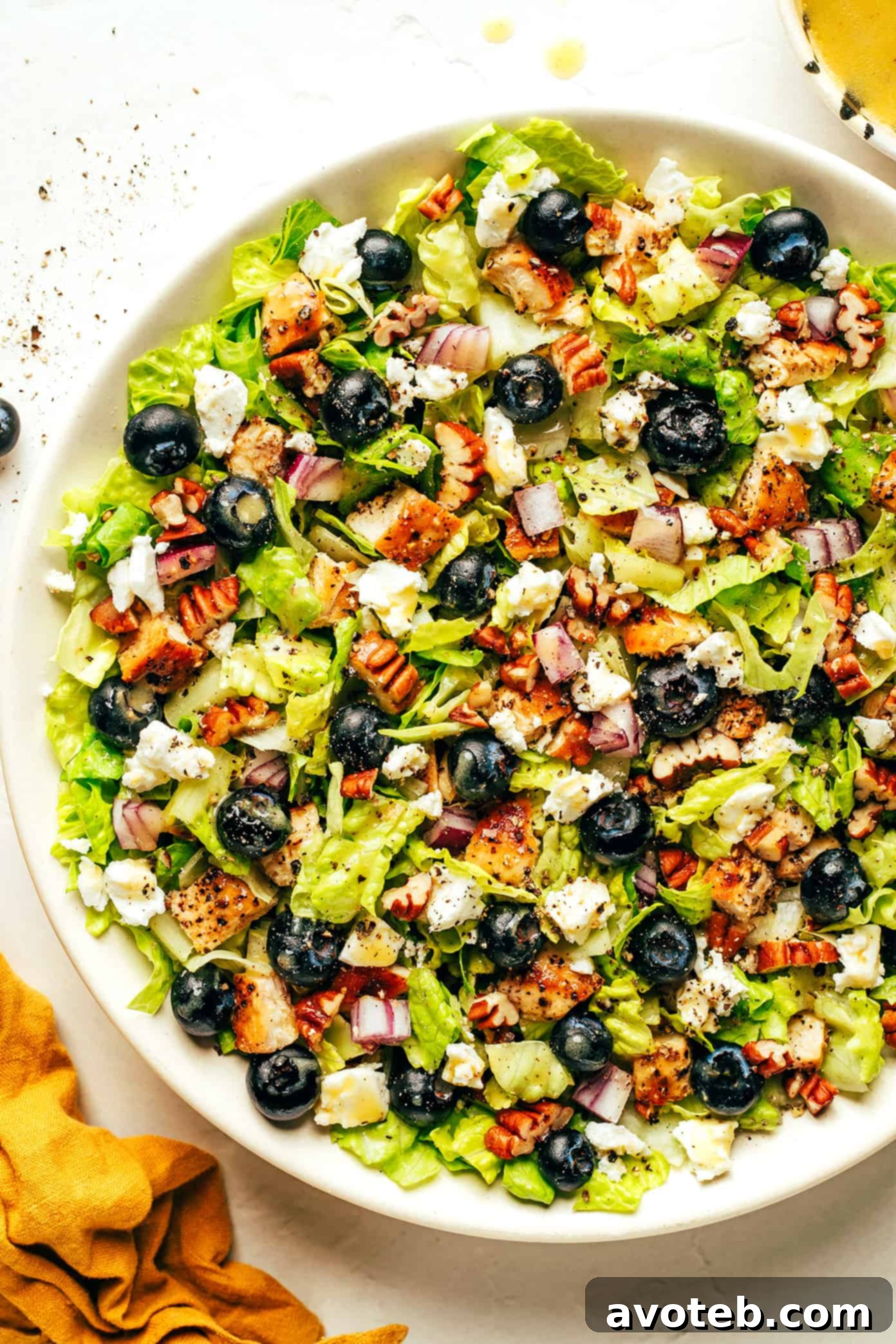 Freshly prepared Blueberry Chicken Chopped Salad in a large bowl, garnished with blueberries, chicken, feta cheese, and pecans, ready to be served.