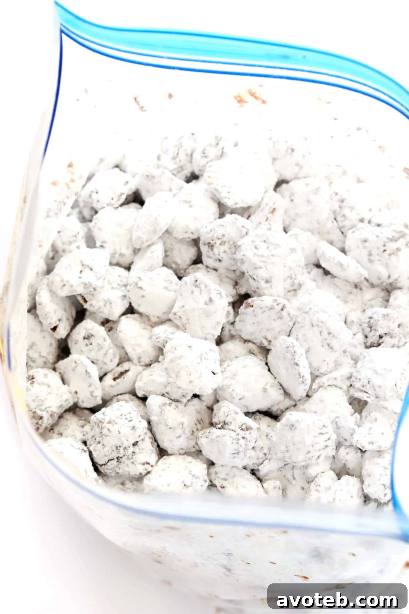 Chocolate Peanut Butter Dusted Bites 7 Finished Puppy Chow (Muddy Buddies) spread on parchment paper.
