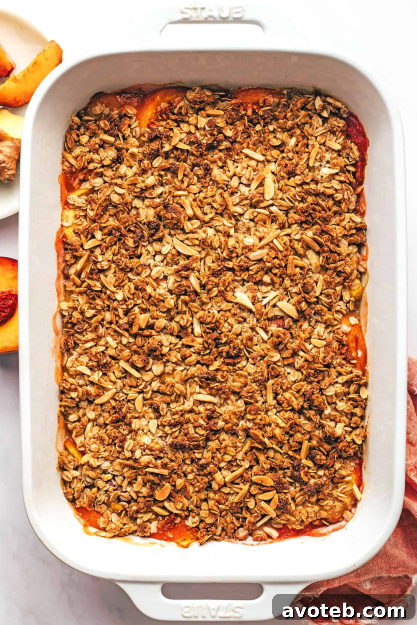 A freshly baked ginger peach crisp in a baking dish, golden brown and bubbling at the edges.