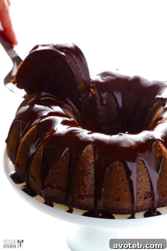 The finished Greek Yogurt Chocolate Cake, adorned with its shiny butter-based glaze, presented beautifully on a cake stand. This image captures the inviting appeal of a homemade dessert that's both elegant and comforting.