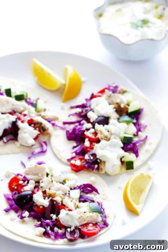 A hand assembling a Greek Fish Taco, layering all fresh ingredients on a tortilla
