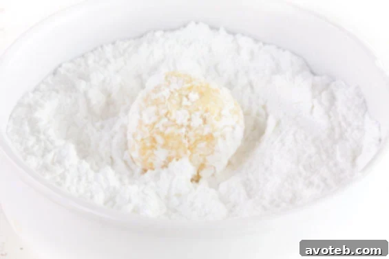 A close-up of a stack of freshly baked lemon cookies, some coated in powdered sugar, ready to be enjoyed.