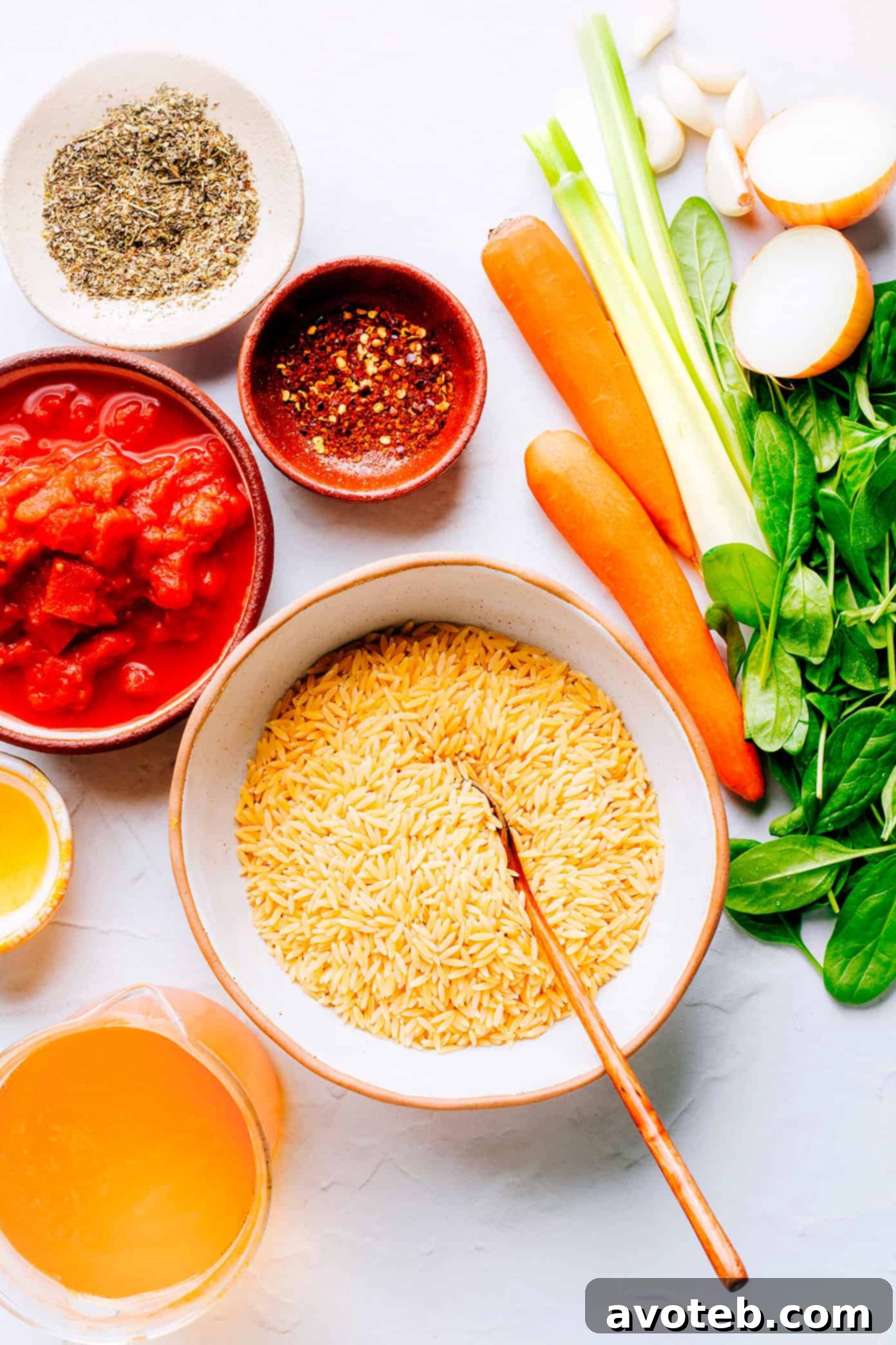 Key ingredients for Italian Orzo Spinach Soup displayed on a wooden board
