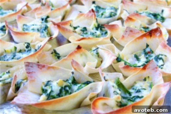 A serving tray filled with freshly baked Spinach and Artichoke Cups, garnished with herbs.