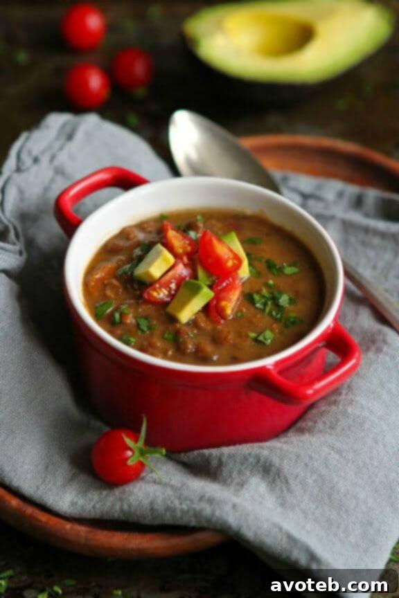 A vibrant bowl of Slow Cooker Chipotle Lentil Soup with Avocado, offering a smoky and spicy flavor.
