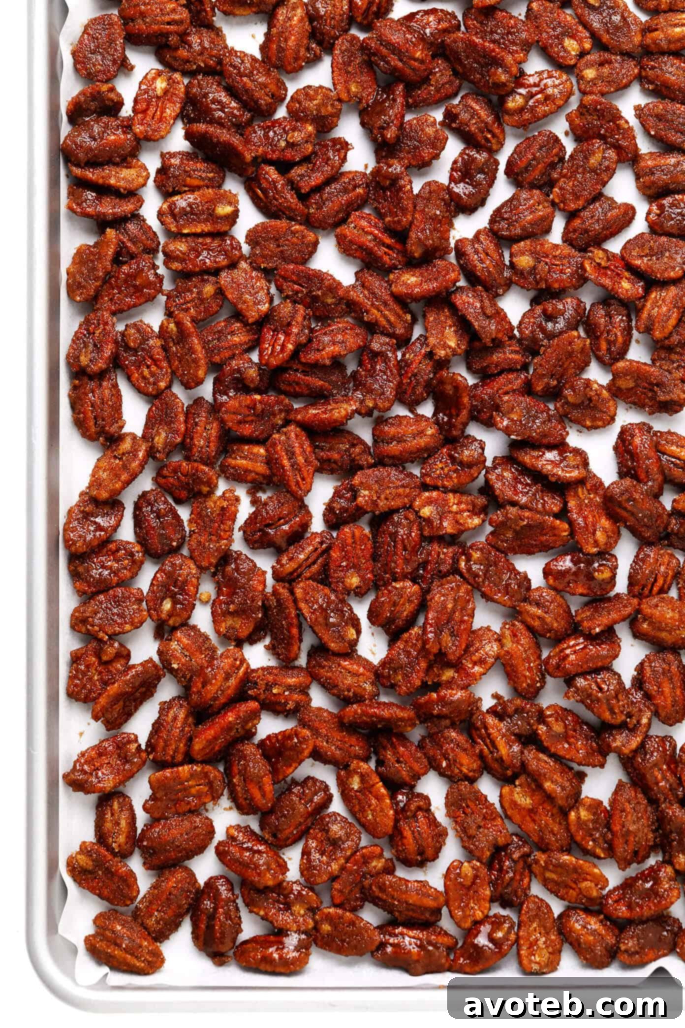Pecans tossed with egg white and sugar mixture on a baking sheet, ready for the oven