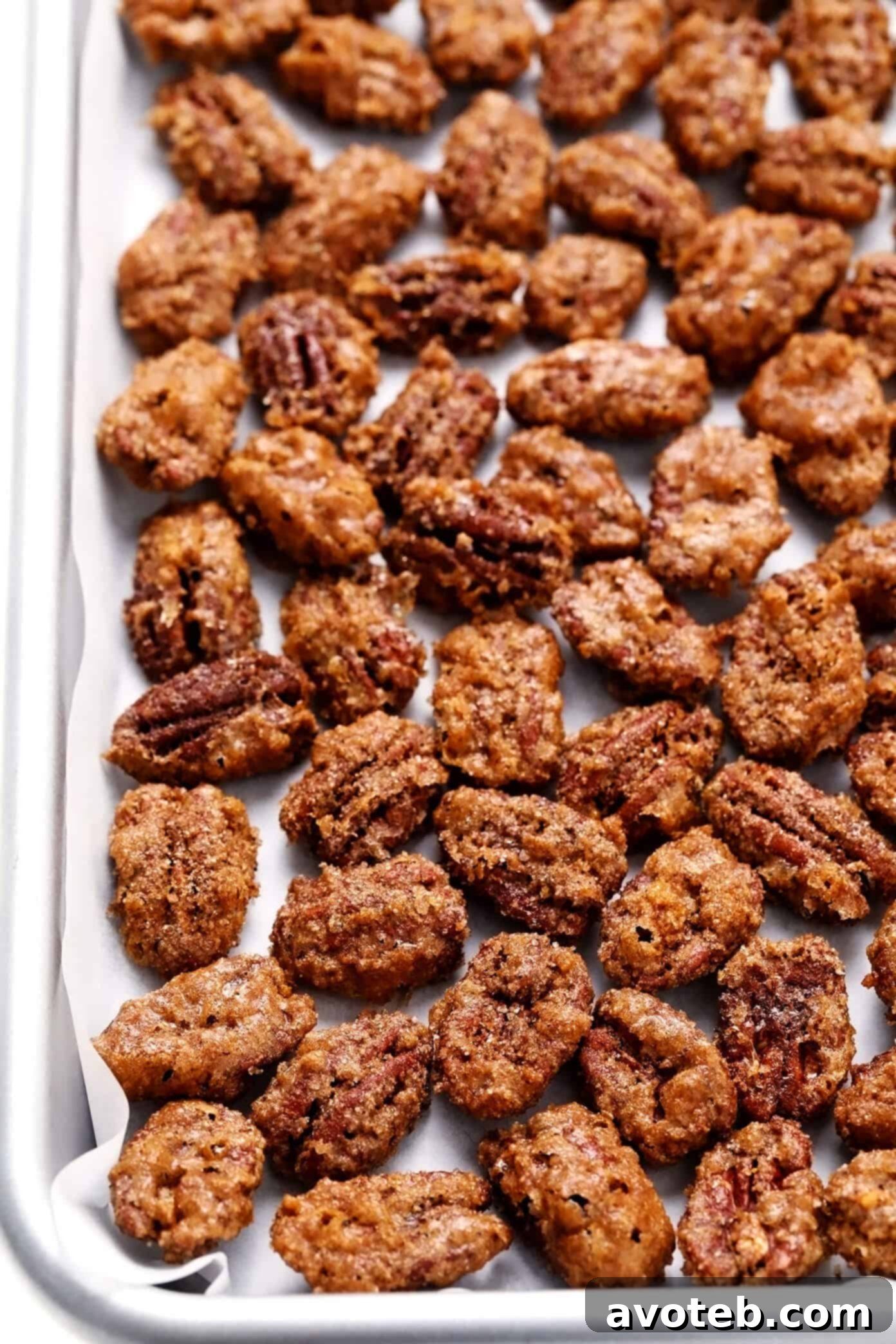 Baked Candied Pecans spread out on a parchment-lined baking sheet to cool