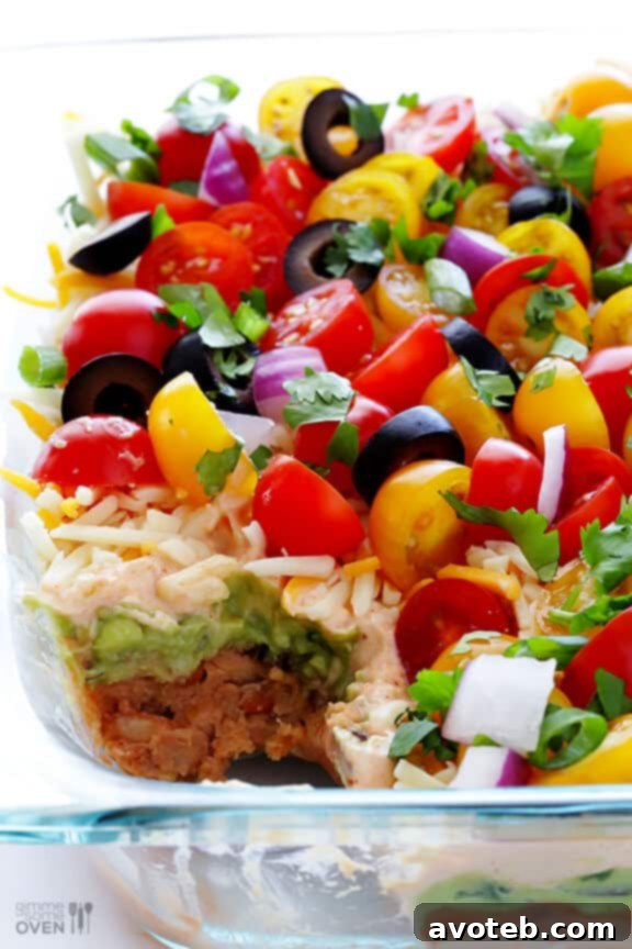 A delicious scoop of 7 Layer Dip on a tortilla chip, ready for enjoyment.