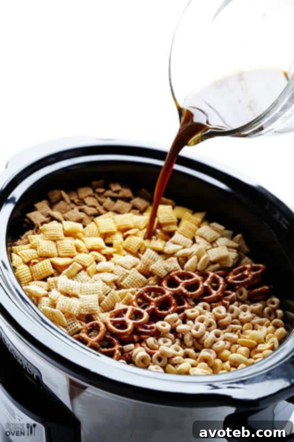 Effortless Slow Cooker Party Mix 5 Pouring seasoning over dry ingredients for Slow Cooker Chex Mix.