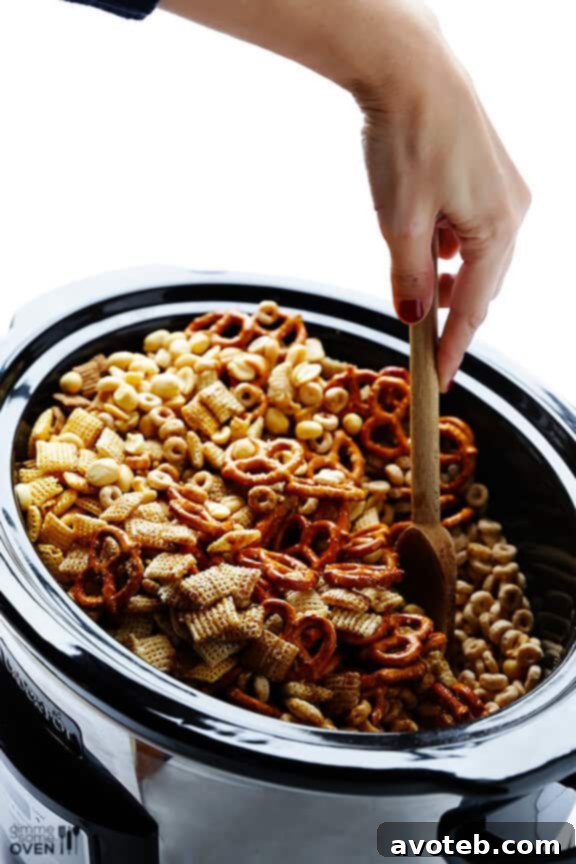 Effortless Slow Cooker Party Mix 6 Stirring Slow Cooker Chex Mix with a rubber spatula.