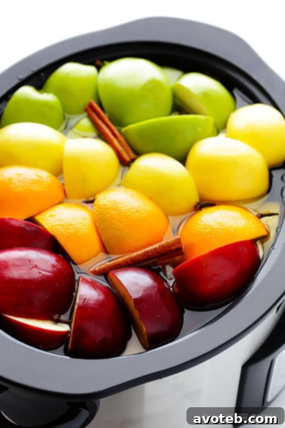 A colorful selection of whole fresh apples and a ripe orange, ready to be prepared for a batch of homemade slow cooker apple cider.