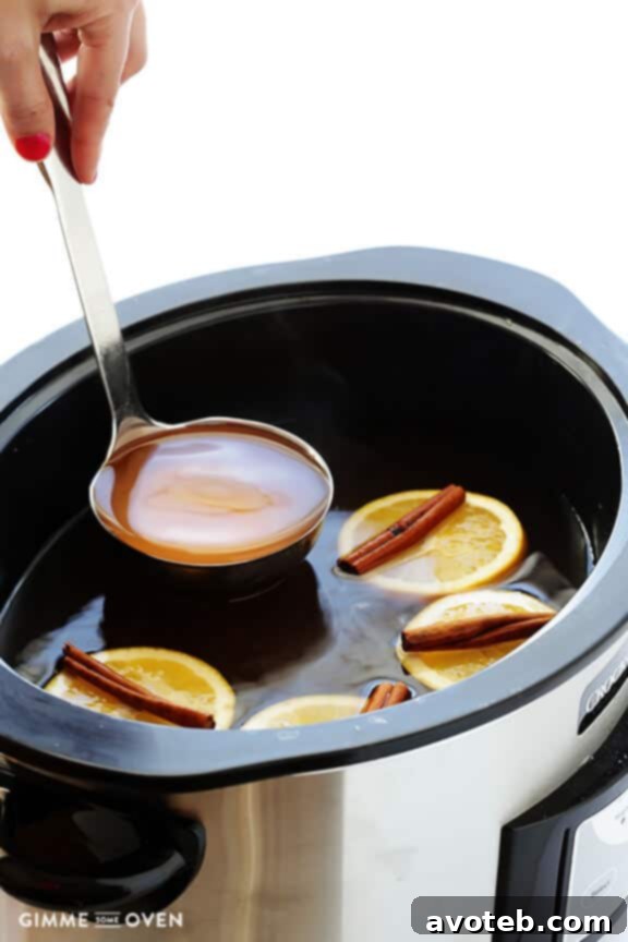 A close-up shot of hot, homemade apple cider being strained through a fine-mesh sieve into a clean, waiting pot, demonstrating the final purification step.