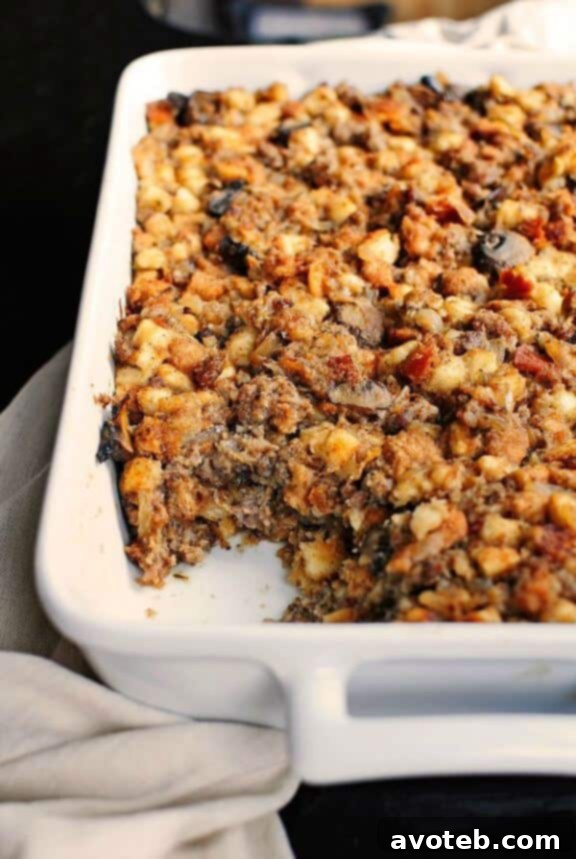A golden-brown baking dish filled with rich Sausage and Mushroom Stuffing, showing its moist, textured surface and savory ingredients, fresh out of the oven.