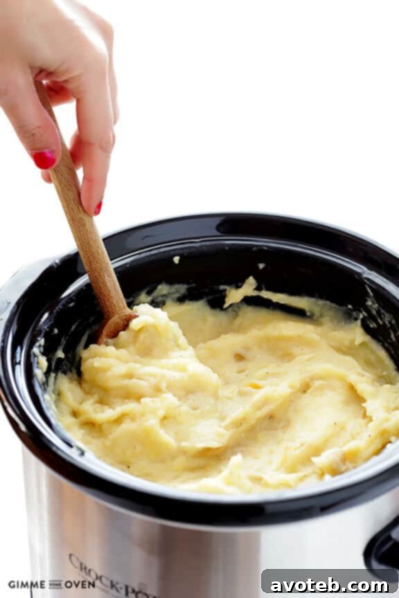 Bowl of finished slow cooker mashed potatoes, garnished and ready to serve.