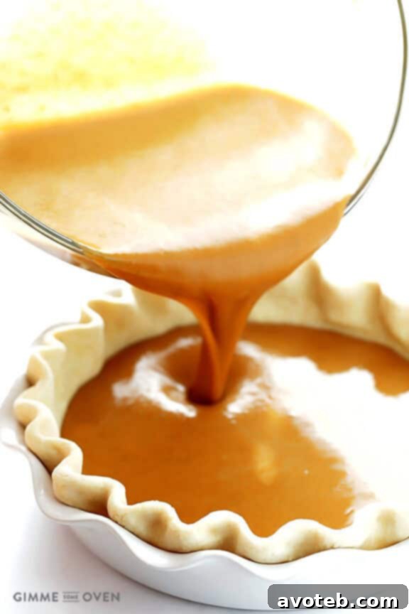 Pouring Bourbon Pumpkin Pie filling into an unbaked pie crust