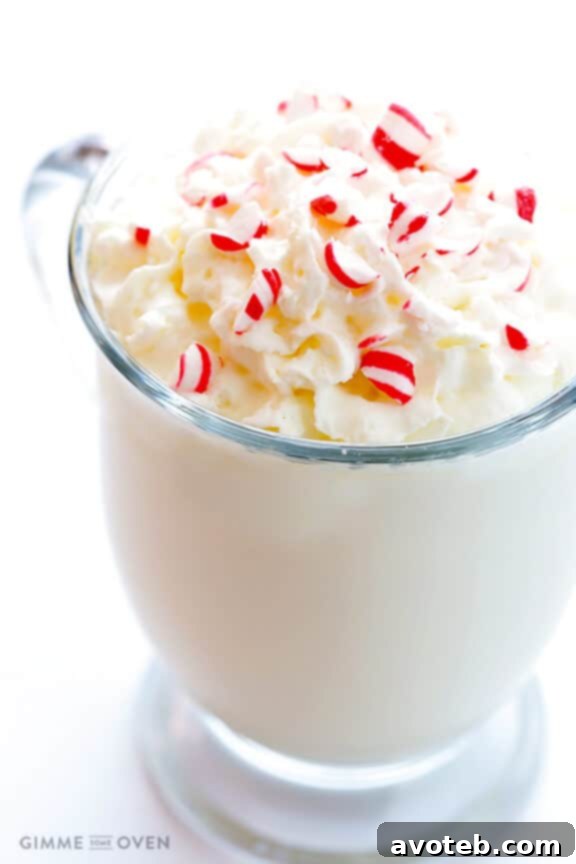 Close-up of a mug of Peppermint White Hot Chocolate, showing the creamy texture and a sprinkle of crushed peppermint on top.