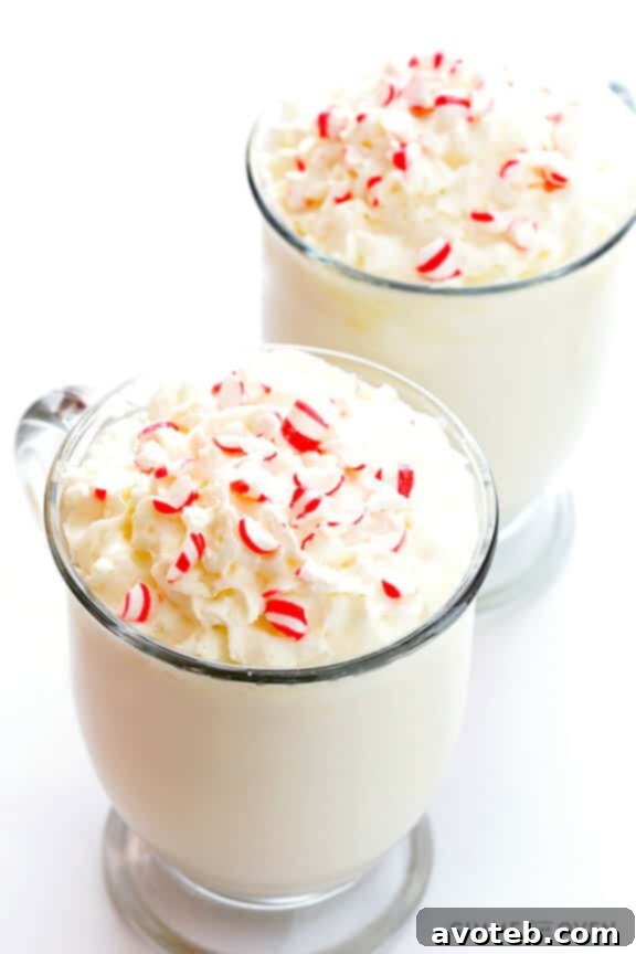 A mug of Peppermint White Hot Chocolate with a candy cane handle, steam rising, suggesting a warm and inviting drink.