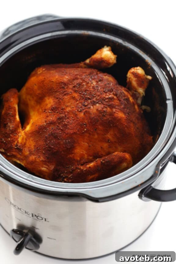 Perfectly seasoned whole chicken cooking in a slow cooker, promising effortless, fall-off-the-bone tenderness.
