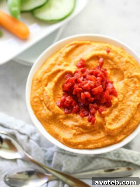 15 Recipes for Creamy Dreamy Hummus Bliss 17 A rich, inviting orange-red Spicy Roasted Red Pepper Hummus, elegantly topped with tender roasted red pepper strips and a sprinkle of chili flakes. This smoky and spicy dip offers a beautiful balance of flavors and vibrant color.