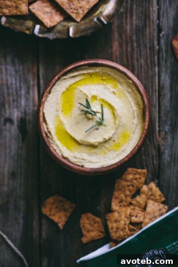 15 Recipes for Creamy Dreamy Hummus Bliss 3 A close-up of fragrant Garlic & Rosemary Hummus, beautifully garnished with fresh rosemary sprigs and a generous drizzle of golden olive oil. This aromatic dip is perfect for special occasions or a gourmet snack.