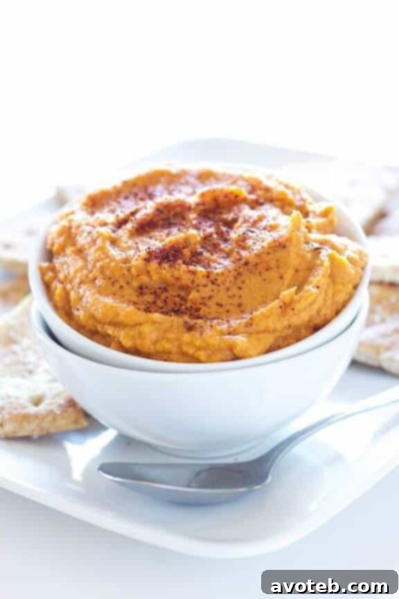 15 Recipes for Creamy Dreamy Hummus Bliss 7 A bowl of vibrant Sriracha Pumpkin Hummus, topped with a fiery swirl of sriracha sauce and a sprinkle of toasted pumpkin seeds. This unique hummus offers a delightful blend of spicy and seasonal flavors.