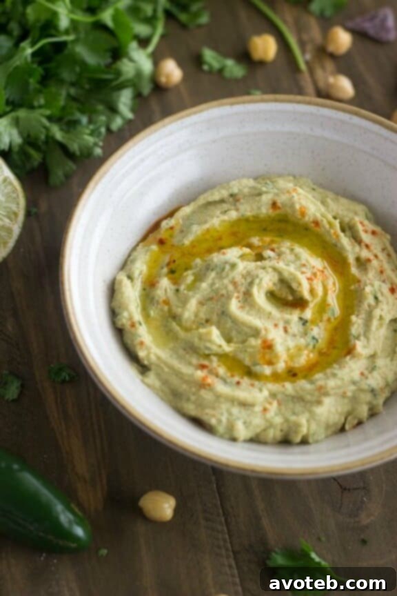 15 Recipes for Creamy Dreamy Hummus Bliss 10 A bright bowl of Jalapeño Lime Hummus, vibrantly garnished with fresh jalapeño slices, zesty lime wedges, and a sprinkle of cilantro. This dip offers a delightful combination of spicy heat and refreshing tang.