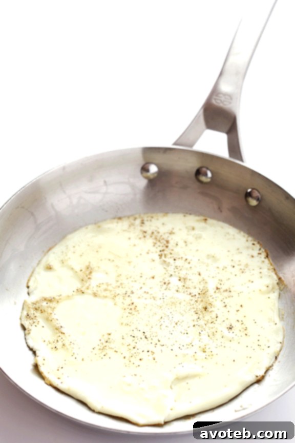 A vibrant Mexican Egg White Omelet, topped with fresh avocado, cilantro, and cotija cheese, ready to be enjoyed.