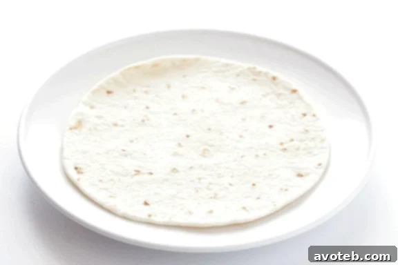 Filling small flour tortillas with refried beans, guacamole, cheese, and chicken
