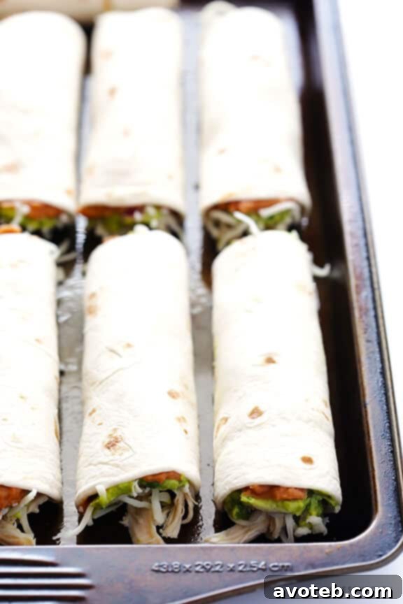Hand rolling a chicken guacamole taquito before baking