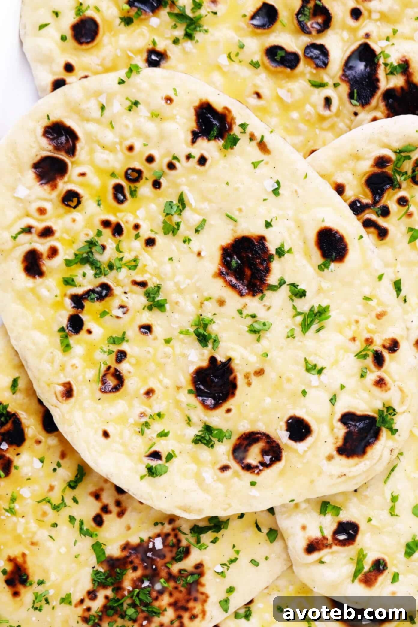 Behold a perfect stack of homemade garlic naan! Experience the warmth, softness, and rich flavor of this freshly prepared flatbread, ideal for any meal. #naanbread #garliclover #bakingathome Stack of Golden Homemade Garlic Naan Bread