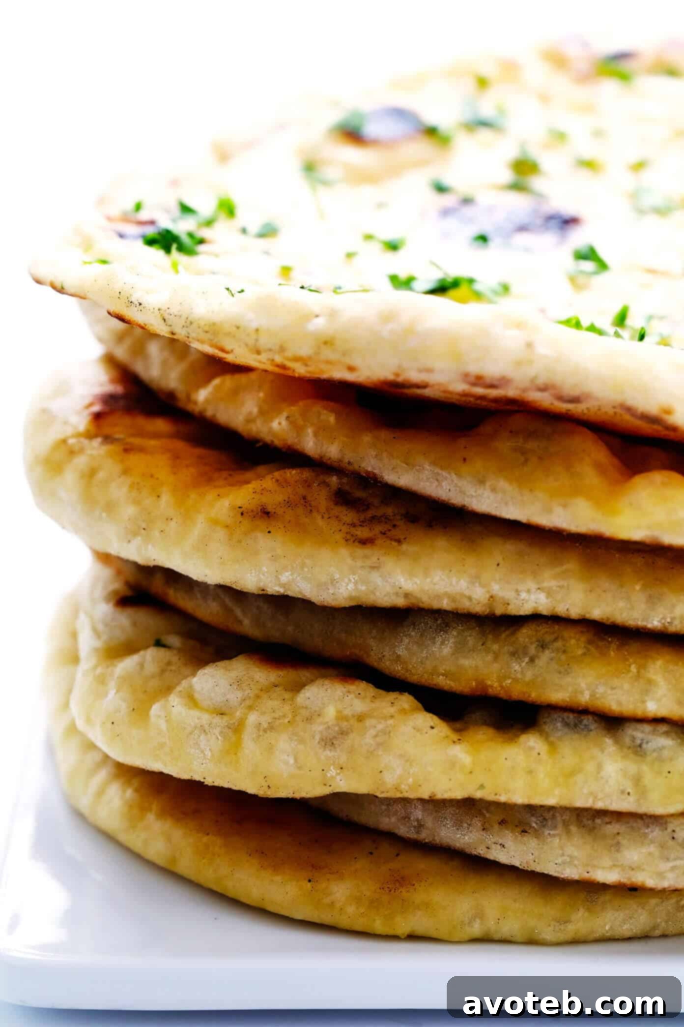 Feast your eyes on this inviting stack of homemade naan bread. Learn to bake this versatile and delicious flatbread that will become a family favorite. #baking #flatbreadrecipe #comfortfood Beautiful Stack of Freshly Baked Homemade Naan Bread