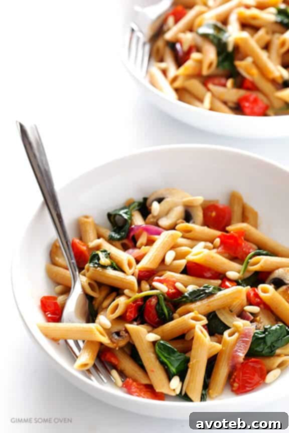 Close-up of freshly prepared Whole Wheat Pasta with Mushrooms, Tomatoes, and Spinach, showcasing the vibrant colors and creamy white wine garlic sauce.