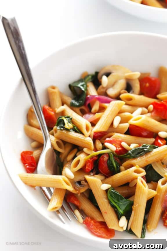 A wide shot of a delicious bowl of Whole Wheat Pasta with Mushrooms, Tomatoes, and Spinach, served hot and ready to eat.