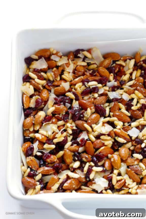 Pouring the warm, sticky binding sauce over the mixed dry ingredients for the Cranberry Almond Protein Bars.
