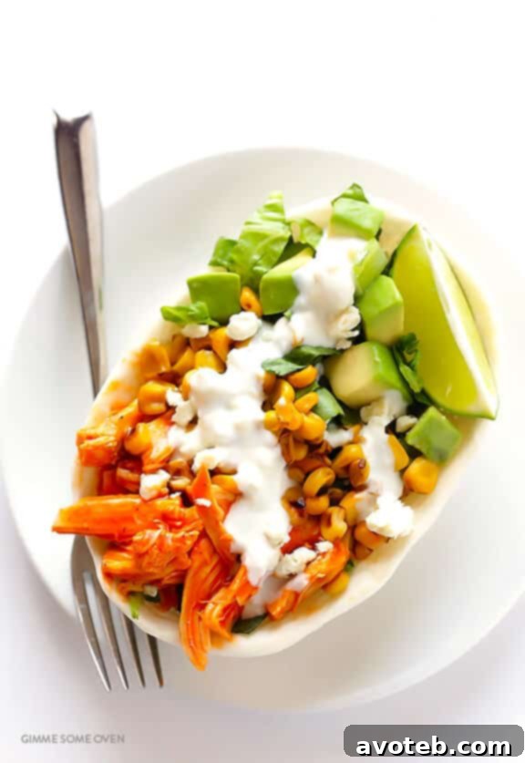 Close-up of a vibrant Buffalo Chicken Taco bowl, showcasing shredded chicken, avocado, corn, and blue cheese dressing.