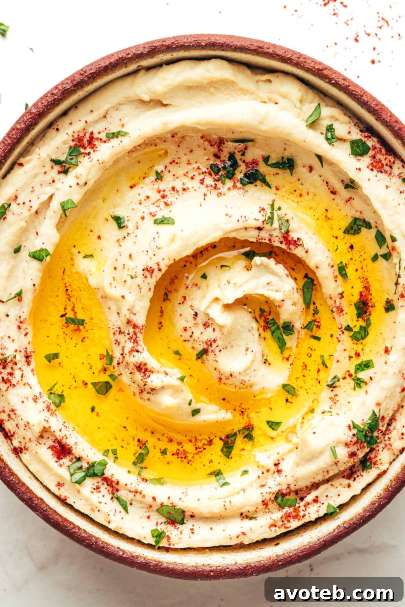 The Art of Hummus 6 A spoon scooping creamy hummus out of a bowl, showcasing its smooth texture.