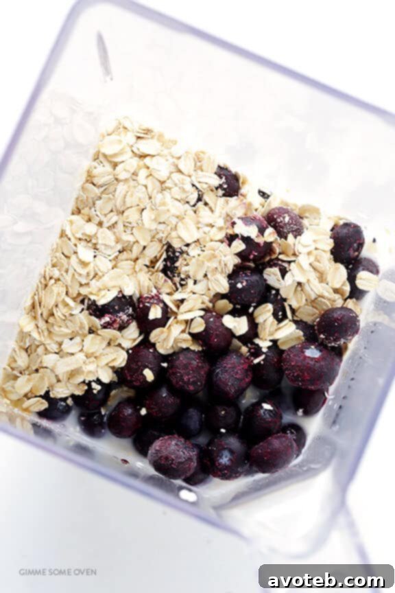 Liquid Blueberry Muffin 4 Ingredients for a Blueberry Muffin Smoothie laid out, including frozen blueberries, oats, and Greek yogurt.