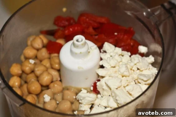 A close-up view of a serving of Roasted Red Pepper and Feta Hummus, showcasing its creamy texture and rich color, garnished and ready for enjoyment.