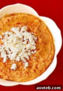 Close-up of a bowl of Roasted Red Pepper and Feta Hummus, vibrant and creamy.