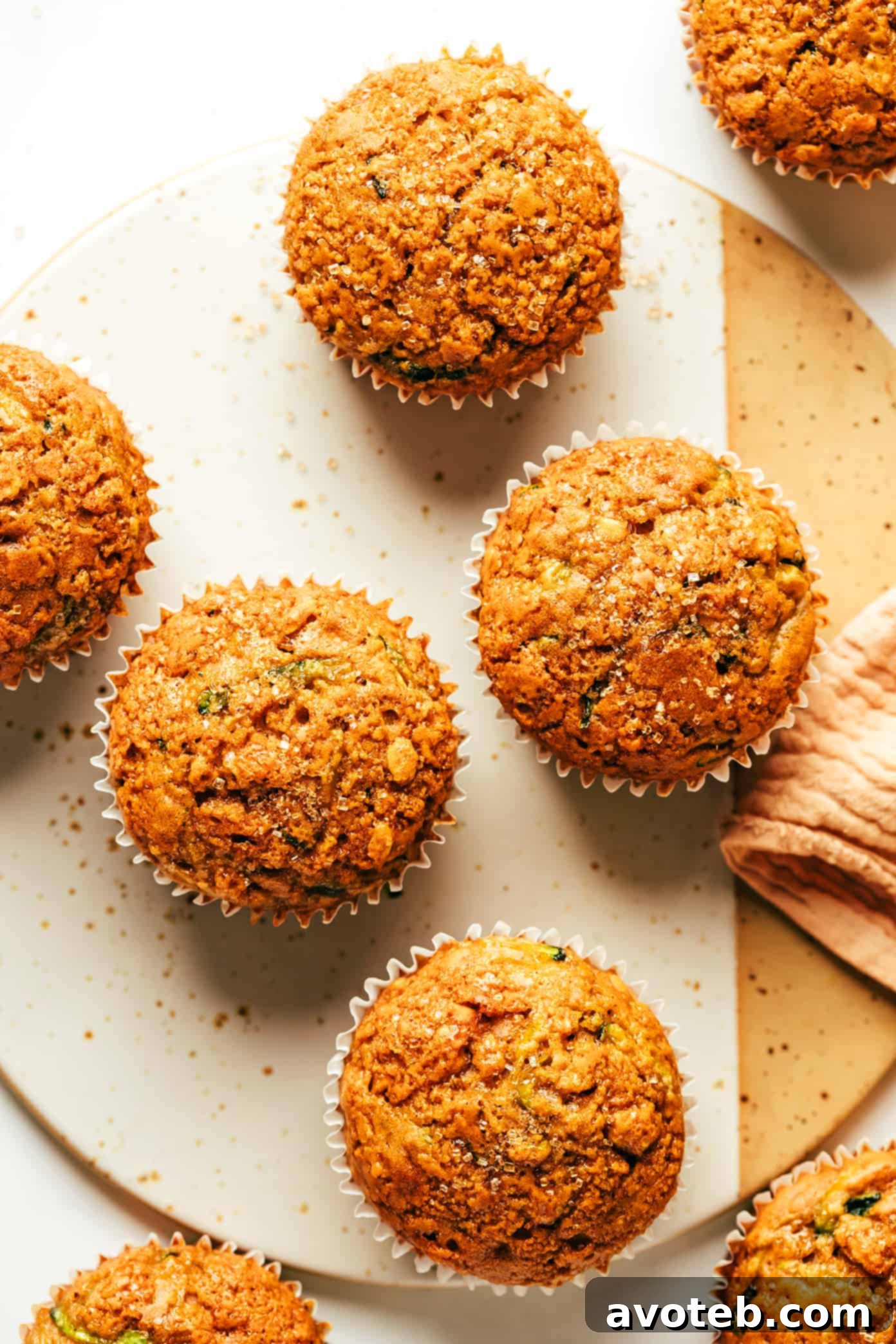 A single healthy zucchini muffin, partially unwrapped from its liner, revealing its tender crumb.