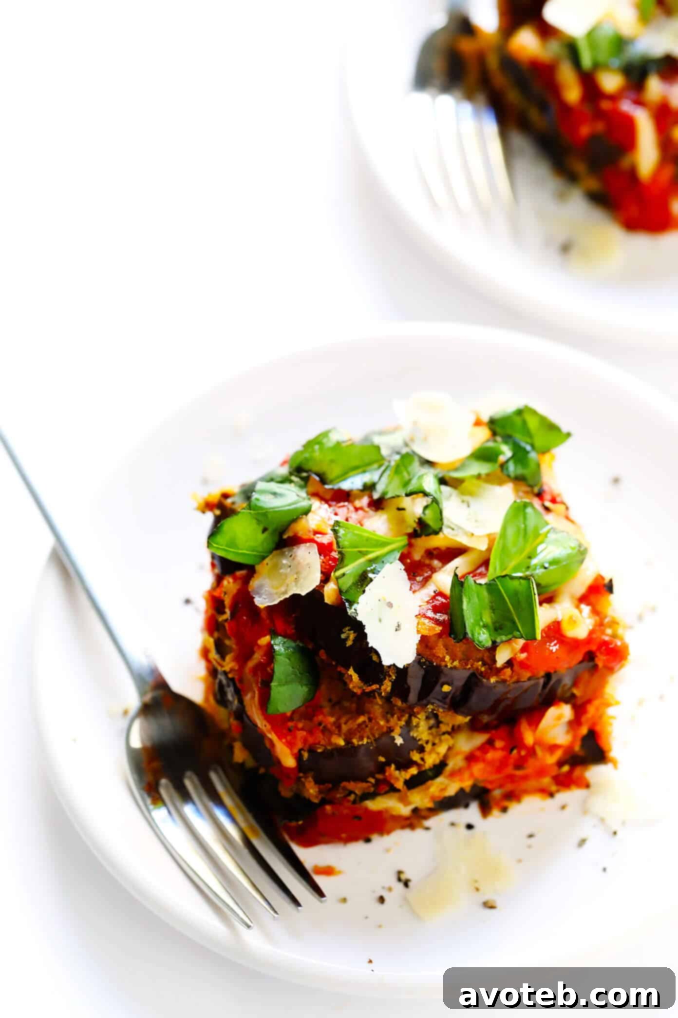 This Baked Eggplant Parmesan recipe is lightened up a bit with Panko-crusted baked (instead of fried) roasted eggplant, and layered with marinara tomato sauce, mozzarella cheese, fresh basil, and lots and lots of Parmesan. It's the perfect vegetarian casserole for Italian night, and always winner! | gimmesomeoven.com #eggplant #parmesan #vegetarian #casserole #glutenfree #italian #comfortfood #lasagna Generous Slice of Baked Eggplant Parmesan with Fresh Basil