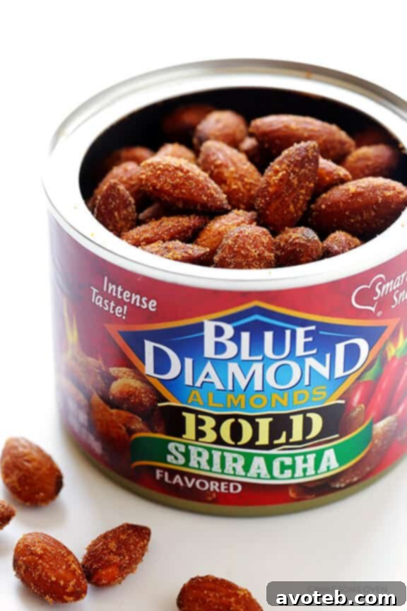 Hand sprinkling fiery Blue Diamond Sriracha Almonds over the wholesome Easy Superfood Quinoa Bowl, adding protein and a spicy crunch.
