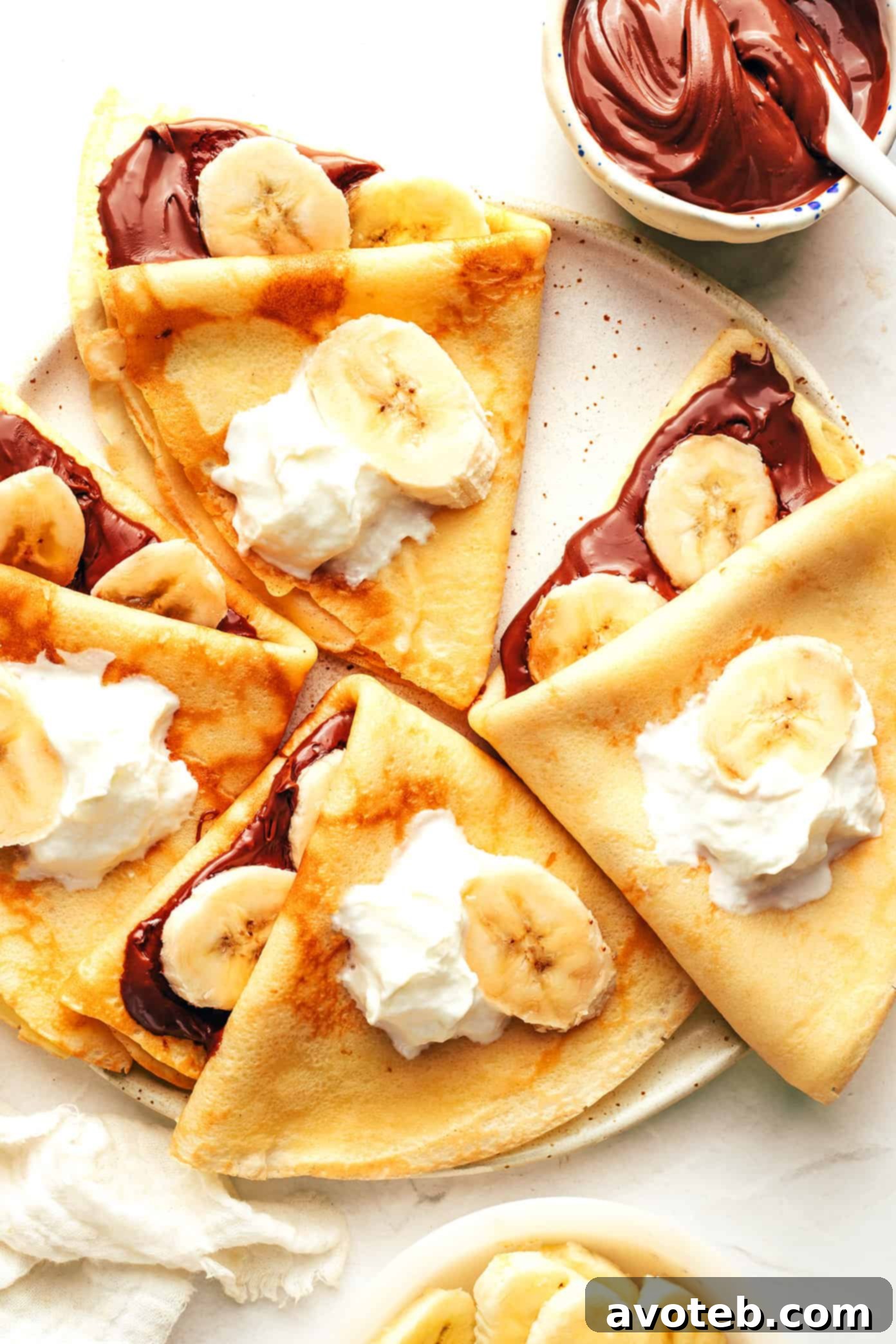 Crepes topped with sliced bananas and Nutella, dusted with powdered sugar