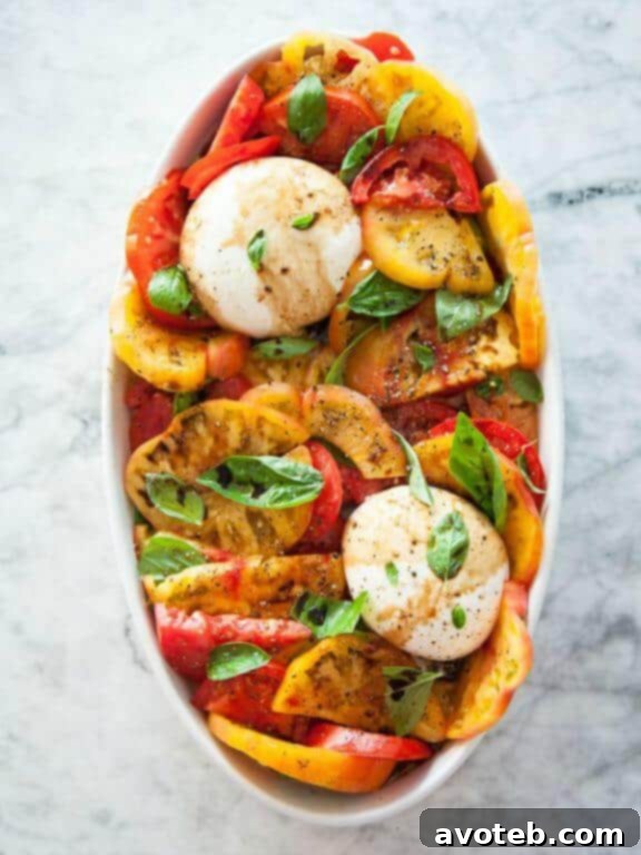 A vibrant Burrata and Heirloom Tomato Caprese Salad, featuring creamy burrata, assorted heirloom tomatoes, and fresh basil leaves.