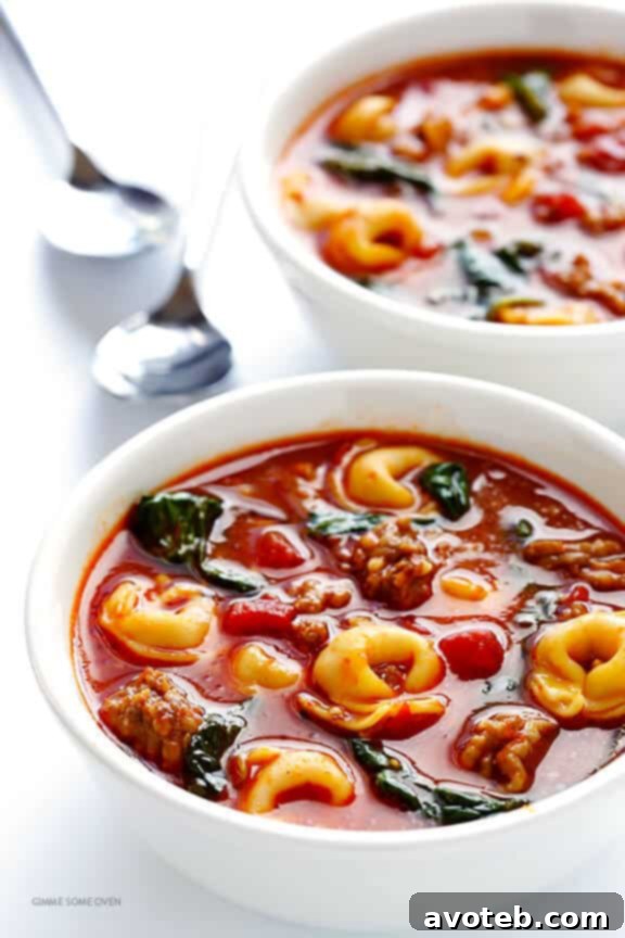 Ingredients for Tortellini Soup laid out on a wooden board, featuring fresh spinach, tortellini, tomatoes, and Italian sausage. | gimmesomeoven.com