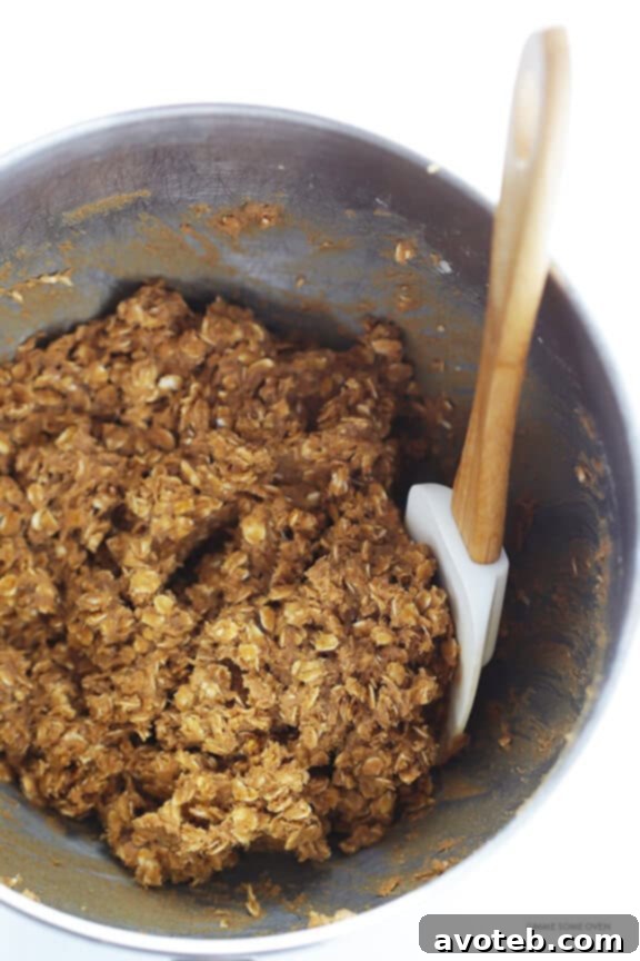 Several Whole Wheat Oatmeal Cookies neatly arranged on a cooling rack, with more cookies visible in the background, showcasing their consistent shape, inviting texture, and overall delicious appeal.