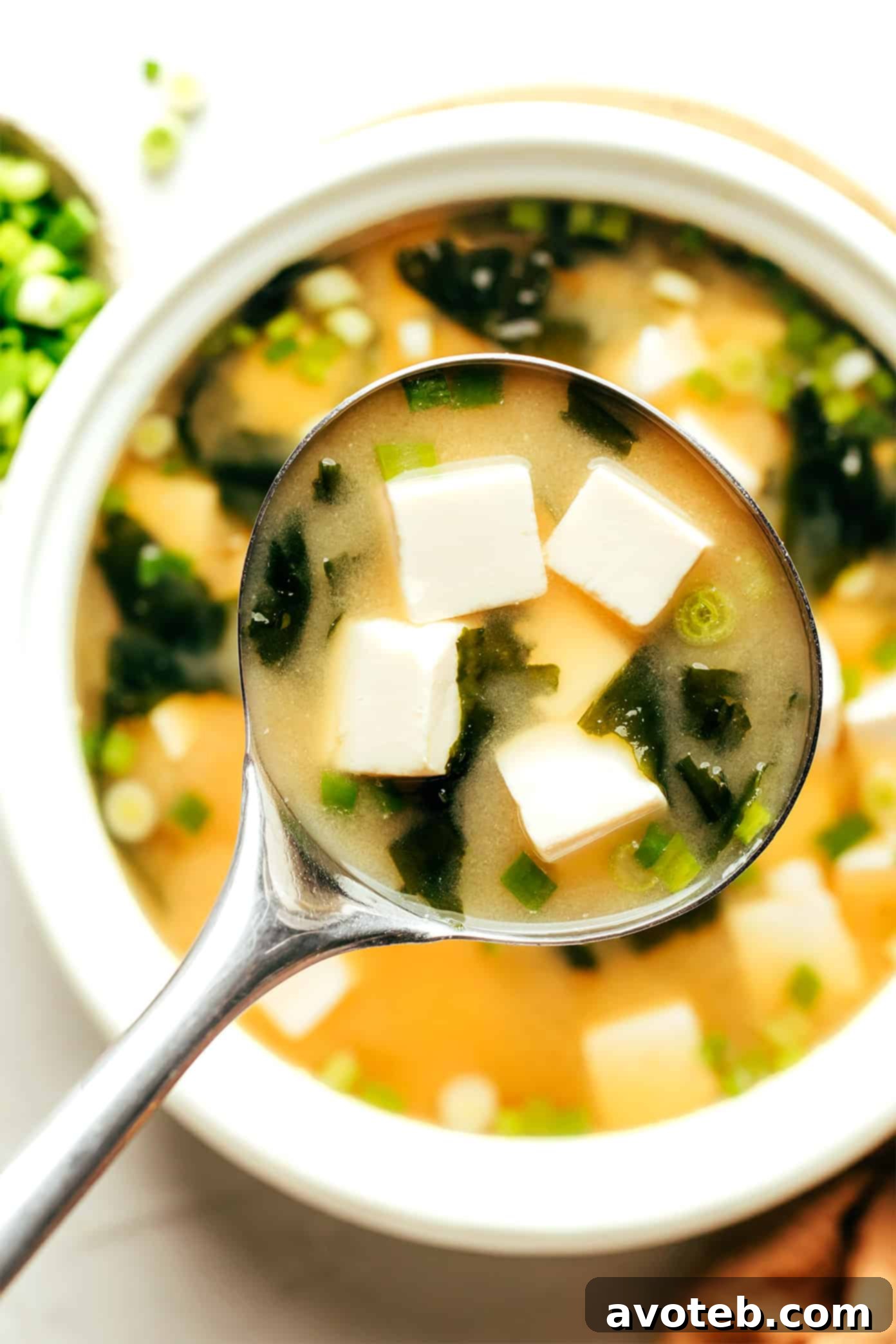 A ladle serving a generous portion of miso soup from a pot, showcasing its rich texture and inviting aroma.